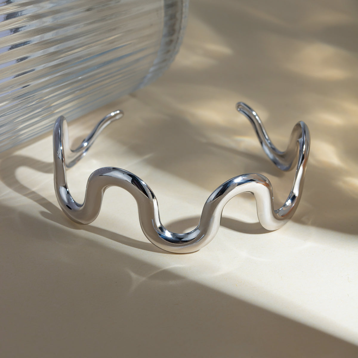 Stainless steel wave shape bracelet on reflective surface