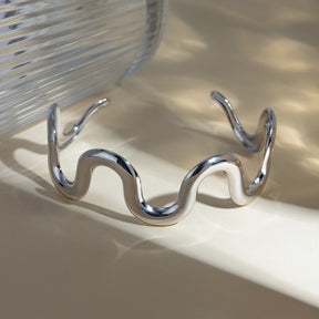 Stainless steel wave shape bracelet on reflective surface