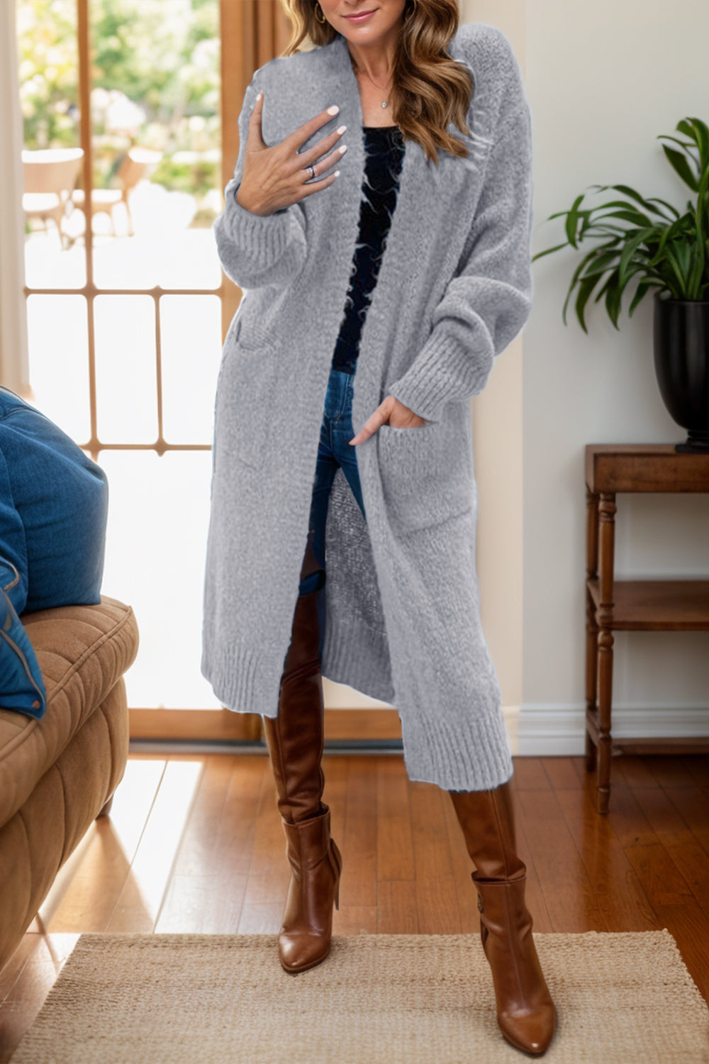 a woman standing in a living room wearing a gray cardigan