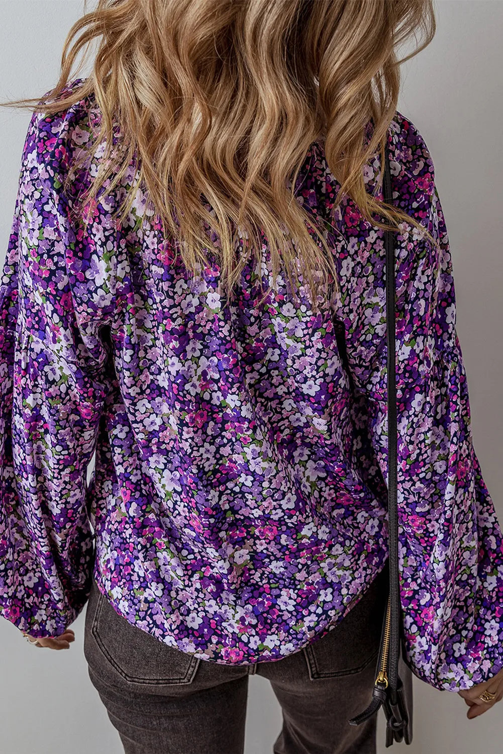 the back of a woman wearing a purple floral blouse