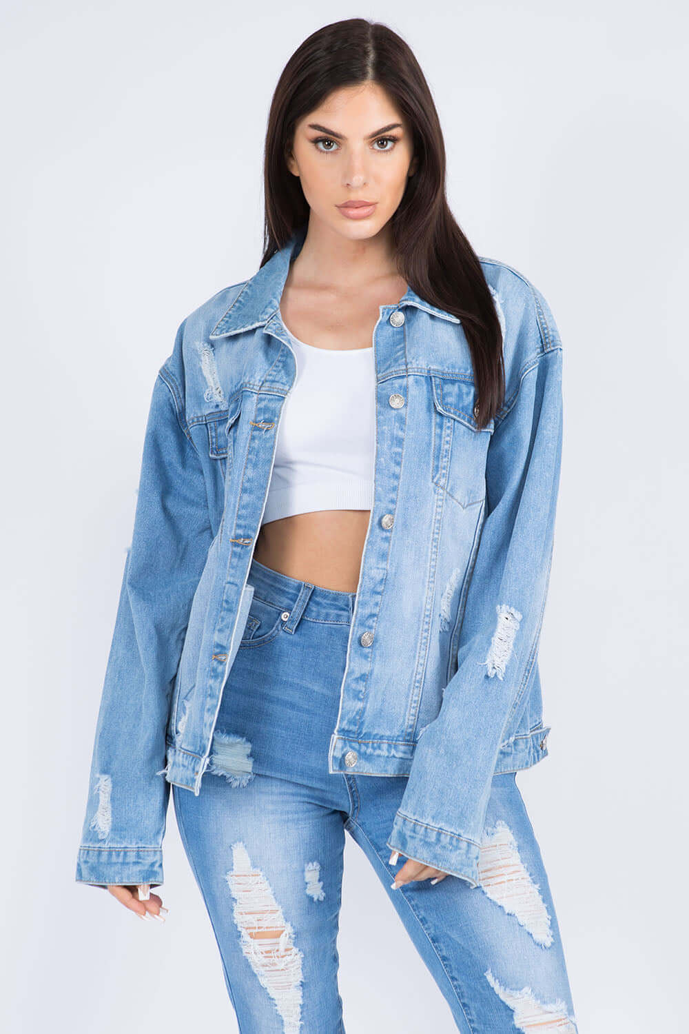 Front view of distressed denim jacket with white top