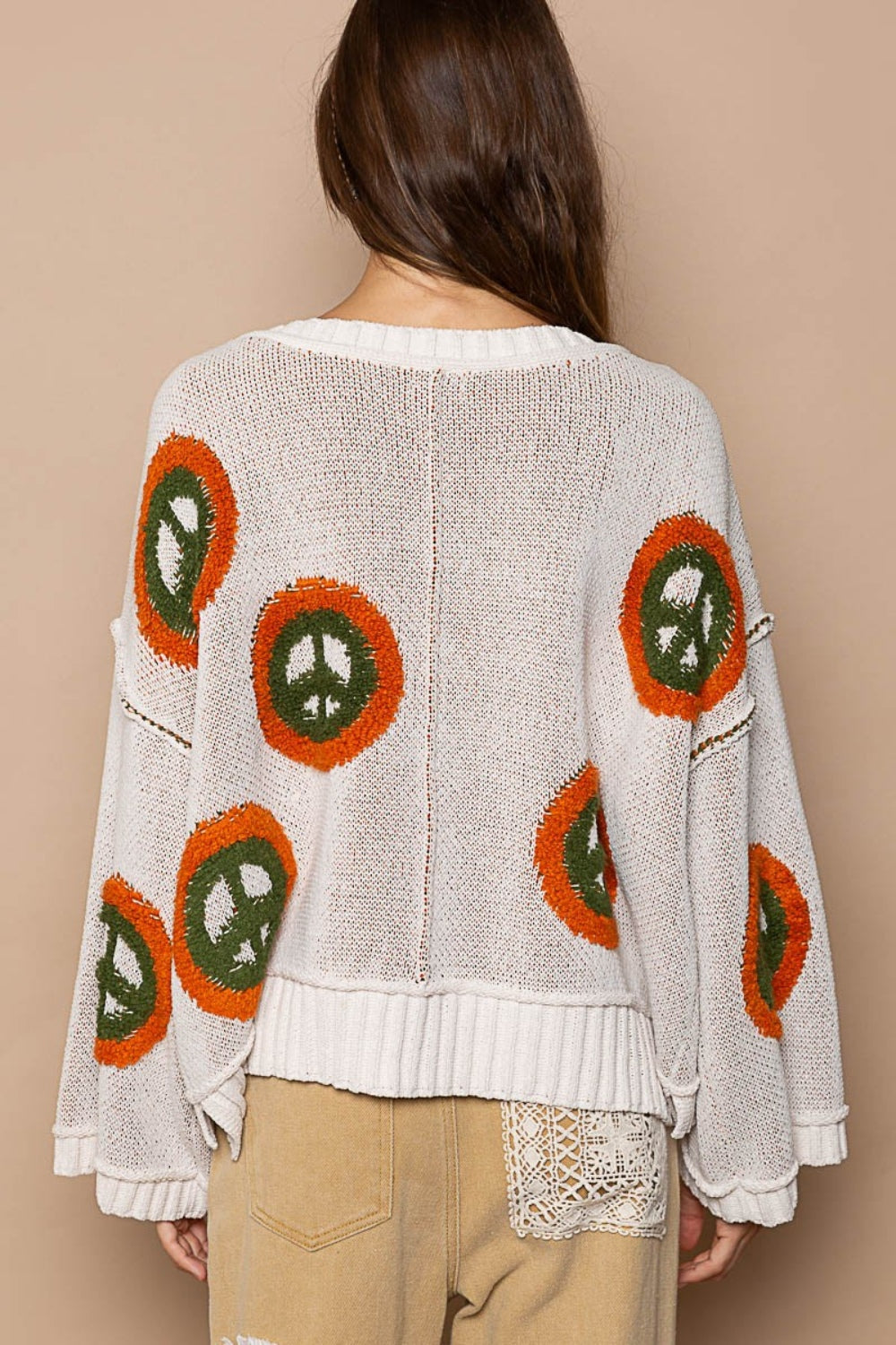 a woman is wearing a peace sign sweater