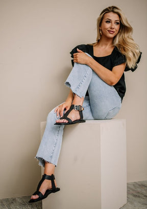 Black AVA 2 flat sandals with buckle, paired with light jeans.