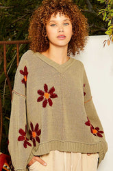 a woman wearing a sweater with flowers on it