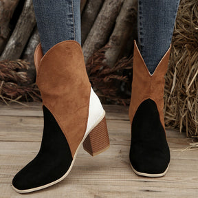 Black and brown suede block heel boots on wooden floor