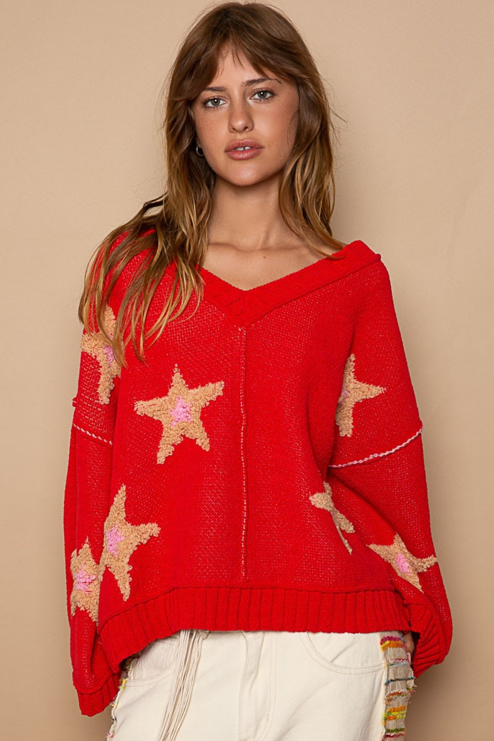 Red long sleeve sweater with star patches, front view.