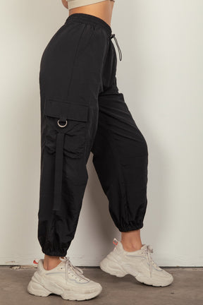 Side view of black cargo pants with utility pockets and D rings