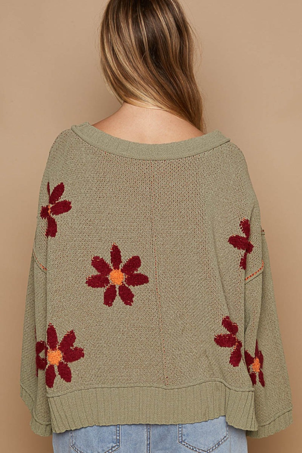 a woman wearing a sweater with flowers on it