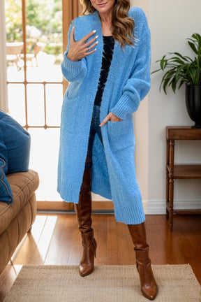 a woman standing in a living room wearing a blue cardigan