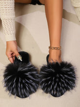 Close-up of fuzzy open toe sandals with black pom-poms