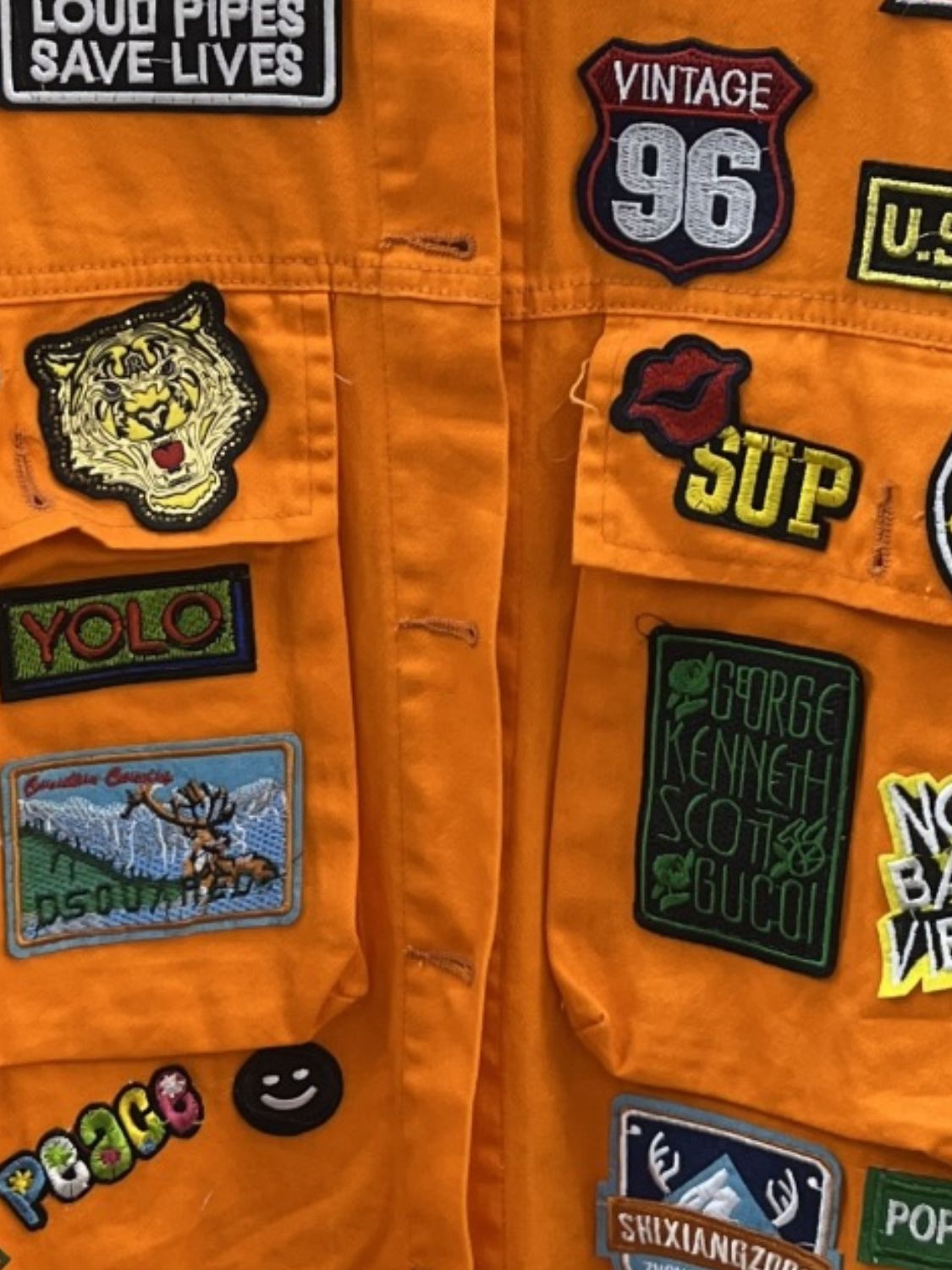 Close-up of patches on orange jacket.