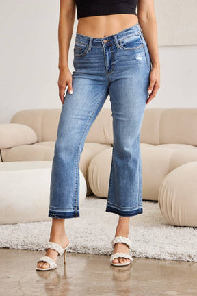 a woman standing in a living room wearing a pair of jeans