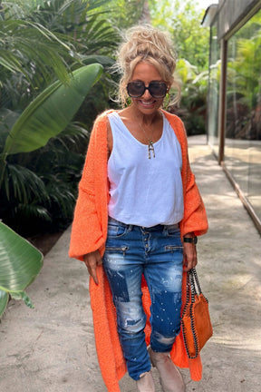 Woman in orange cardigan with white shirt and jeans