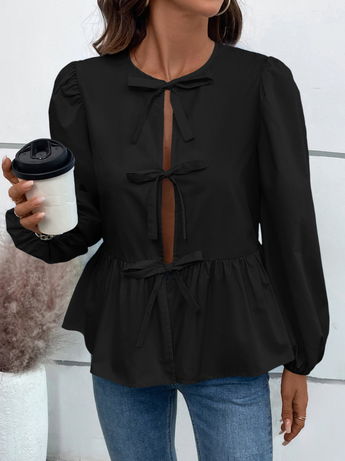 a woman holding a coffee cup and wearing a black top