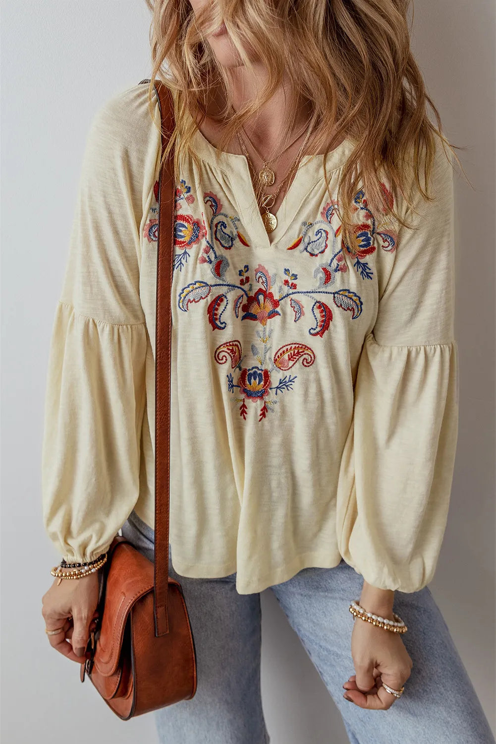 a woman holding a brown purse and wearing a white top