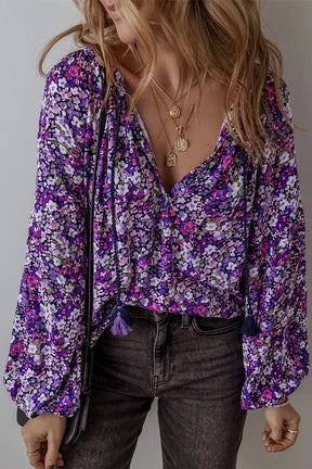 a woman with long hair wearing a purple floral top