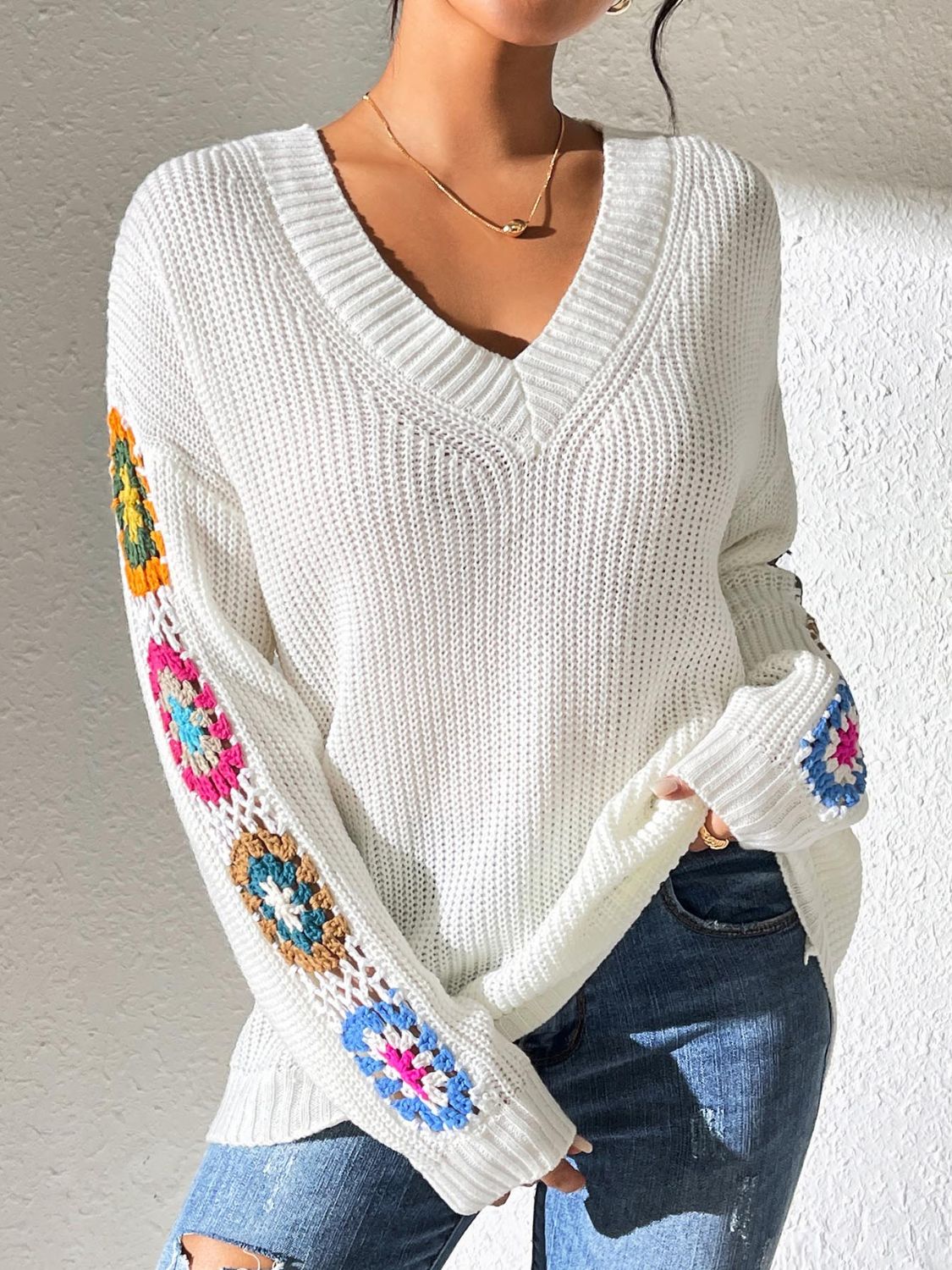 White crochet flower V-neck sweater with colorful sleeves.