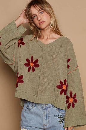 a woman wearing a sweater with flowers on it