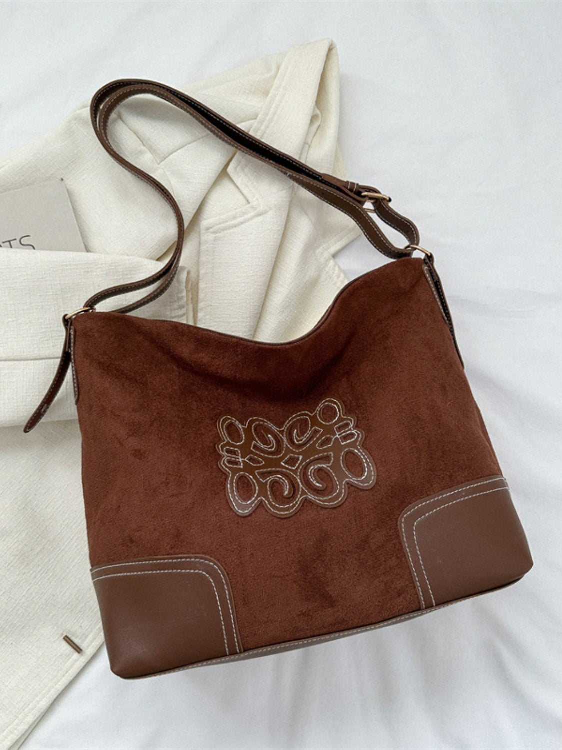 Close-up of suede patch tote bag with zipper detail.