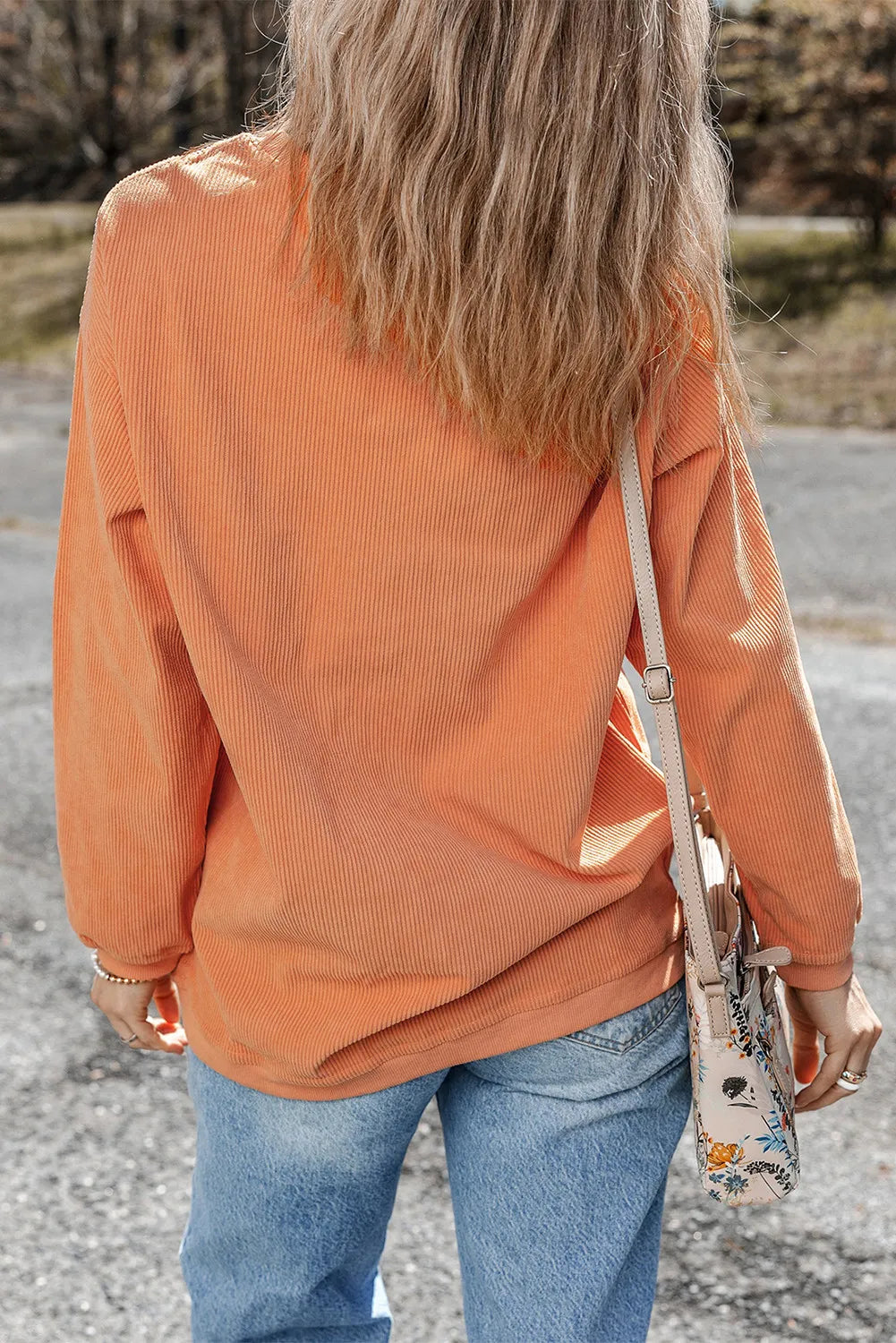 a woman with long hair walking down a street