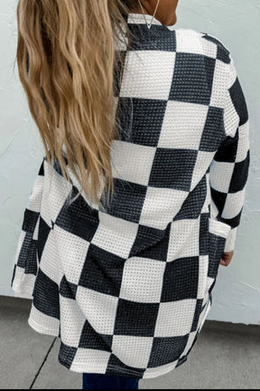 a woman with long hair wearing a black and white checkered sweater