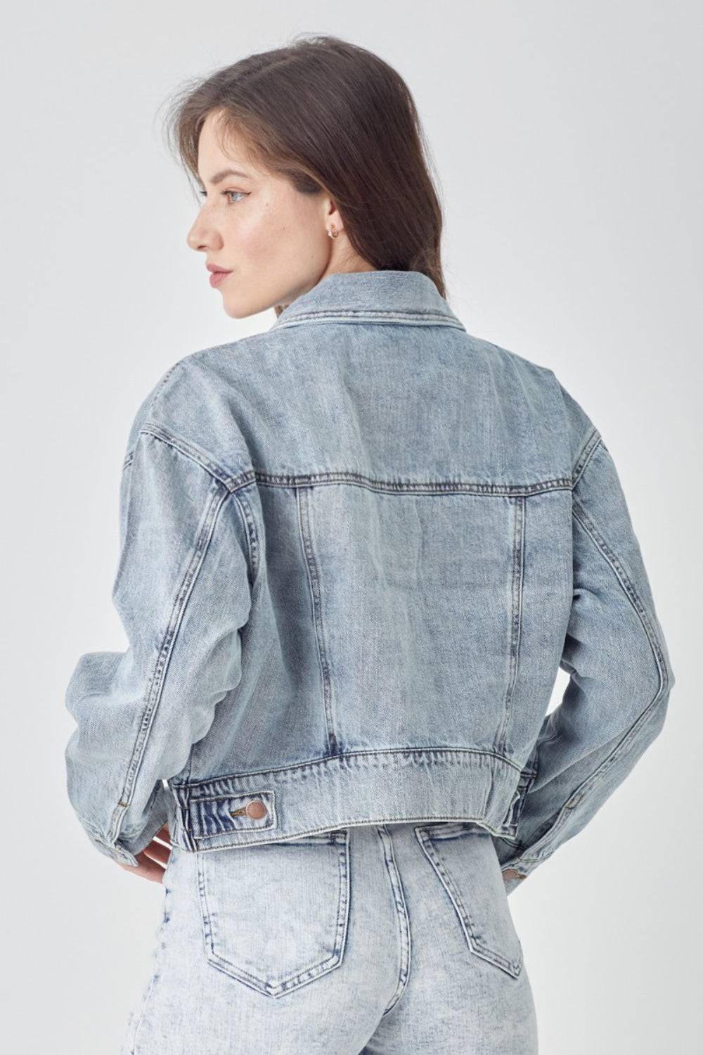 a woman wearing a jean jacket and jeans