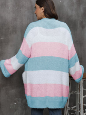 a woman standing next to a chair wearing a pink and blue striped sweater