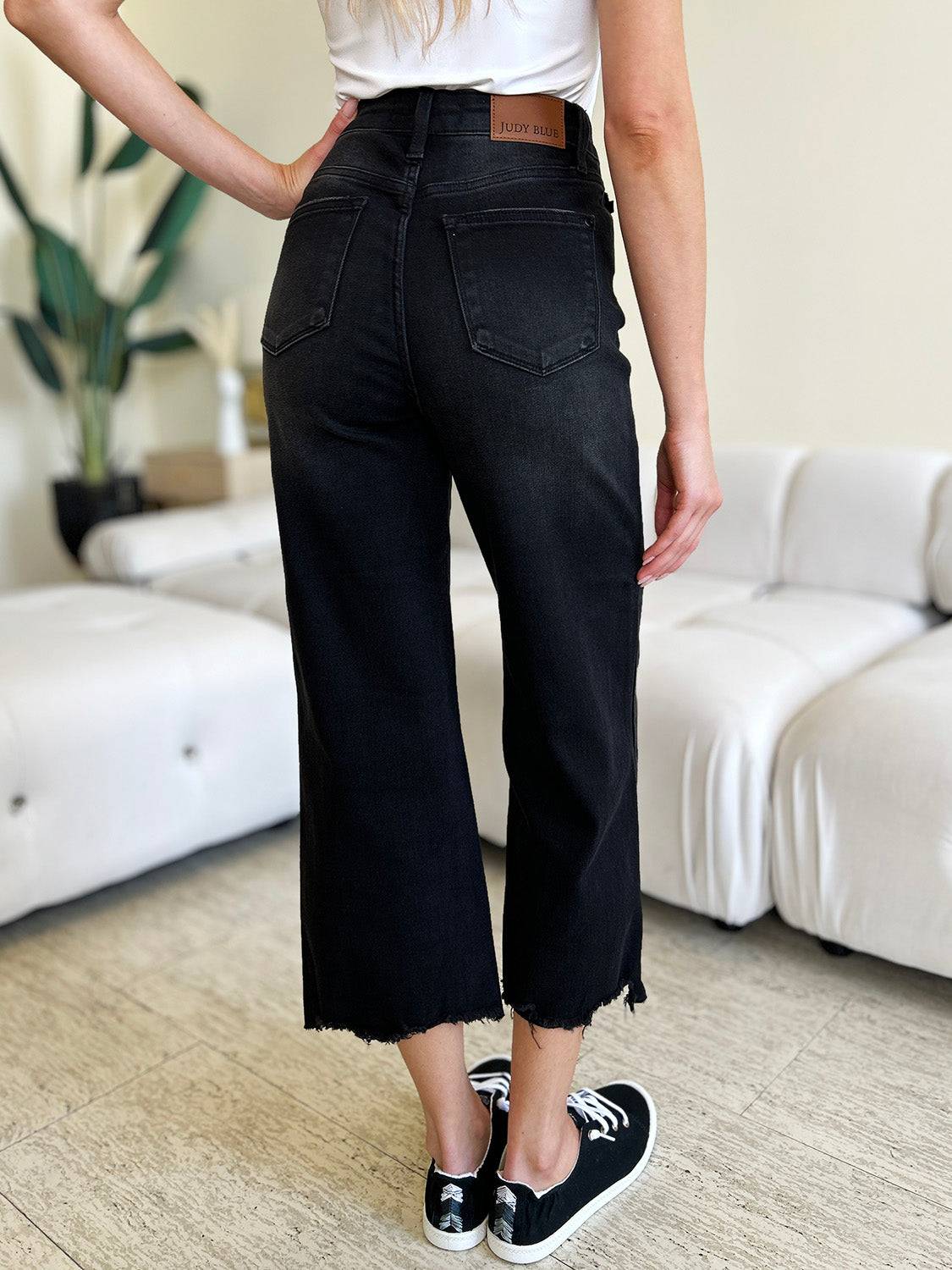 a woman standing in a living room wearing black jeans