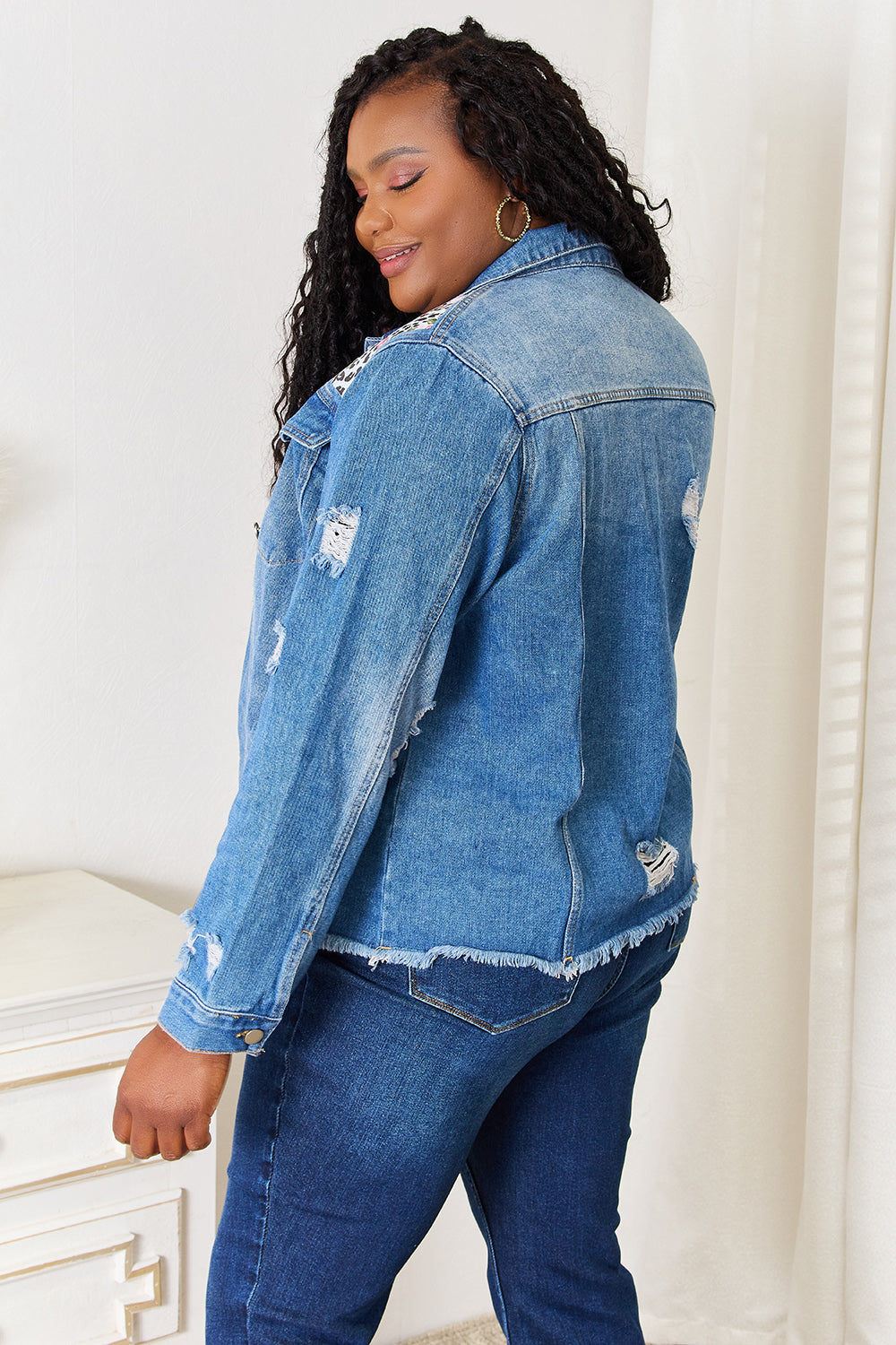 Rear view of plus size distressed denim jacket.