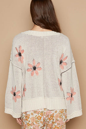 a woman wearing a white sweater with pink flowers on it