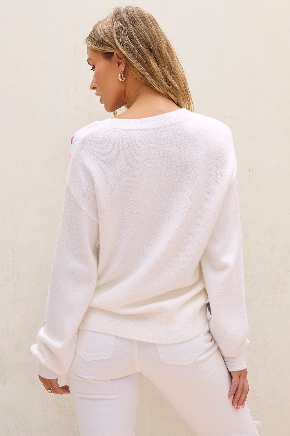 Back view of white sweater with pink crochet flowers.