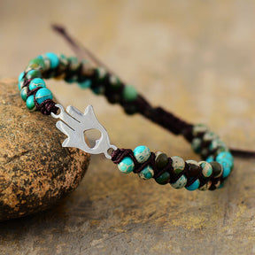 Turquoise beaded bracelet with hand charm on rock