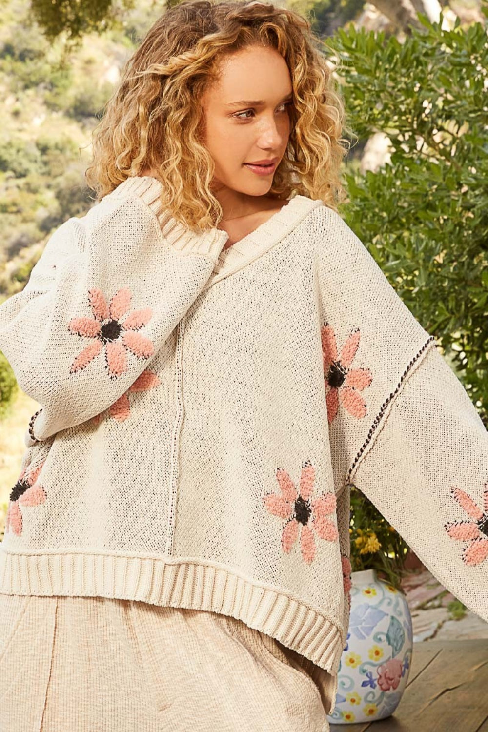 a woman wearing a sweater with flowers on it