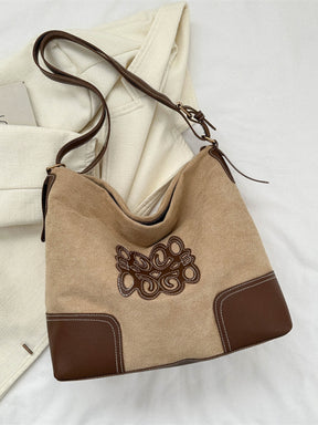 Black suede patch tote bag with adjustable strap and brown accents.