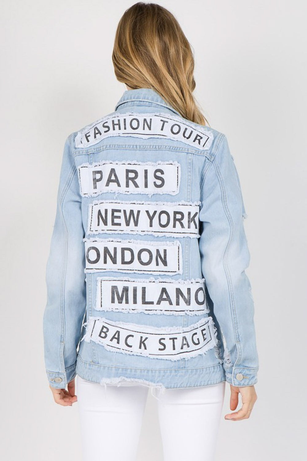 Back view of distressed denim jacket with city patches