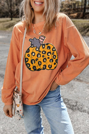 a woman wearing a sweater with a pumpkin on it