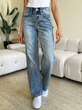 a woman standing in a living room wearing a pair of jeans