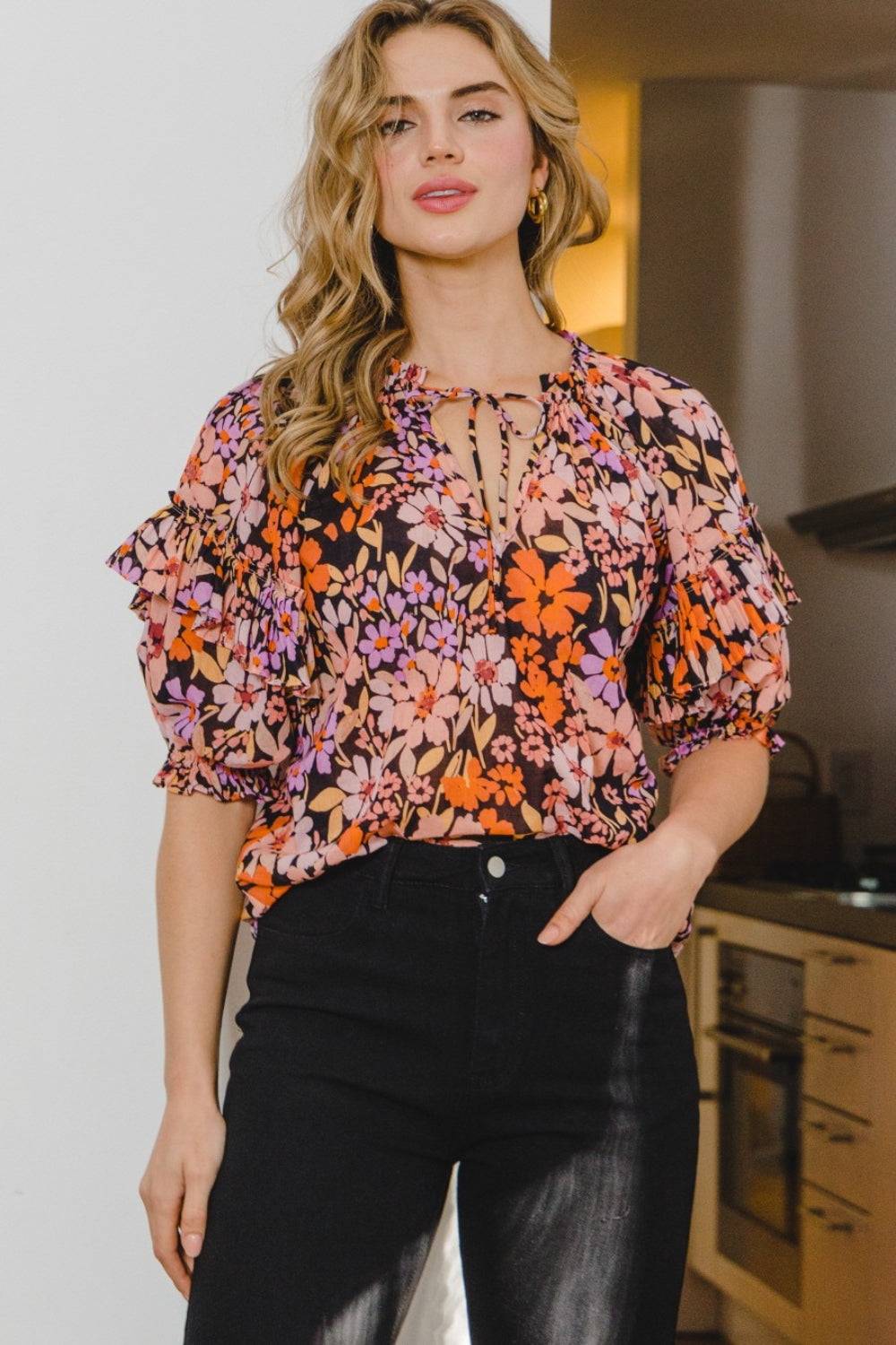 a woman standing in a kitchen wearing a floral top